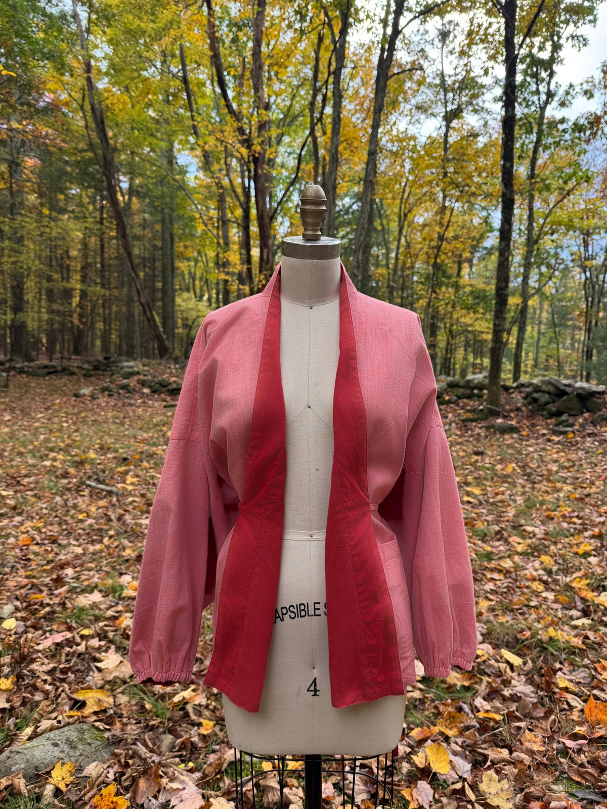 Reversible wrap jacket worn pink side out and open, with the red facing showing down the front