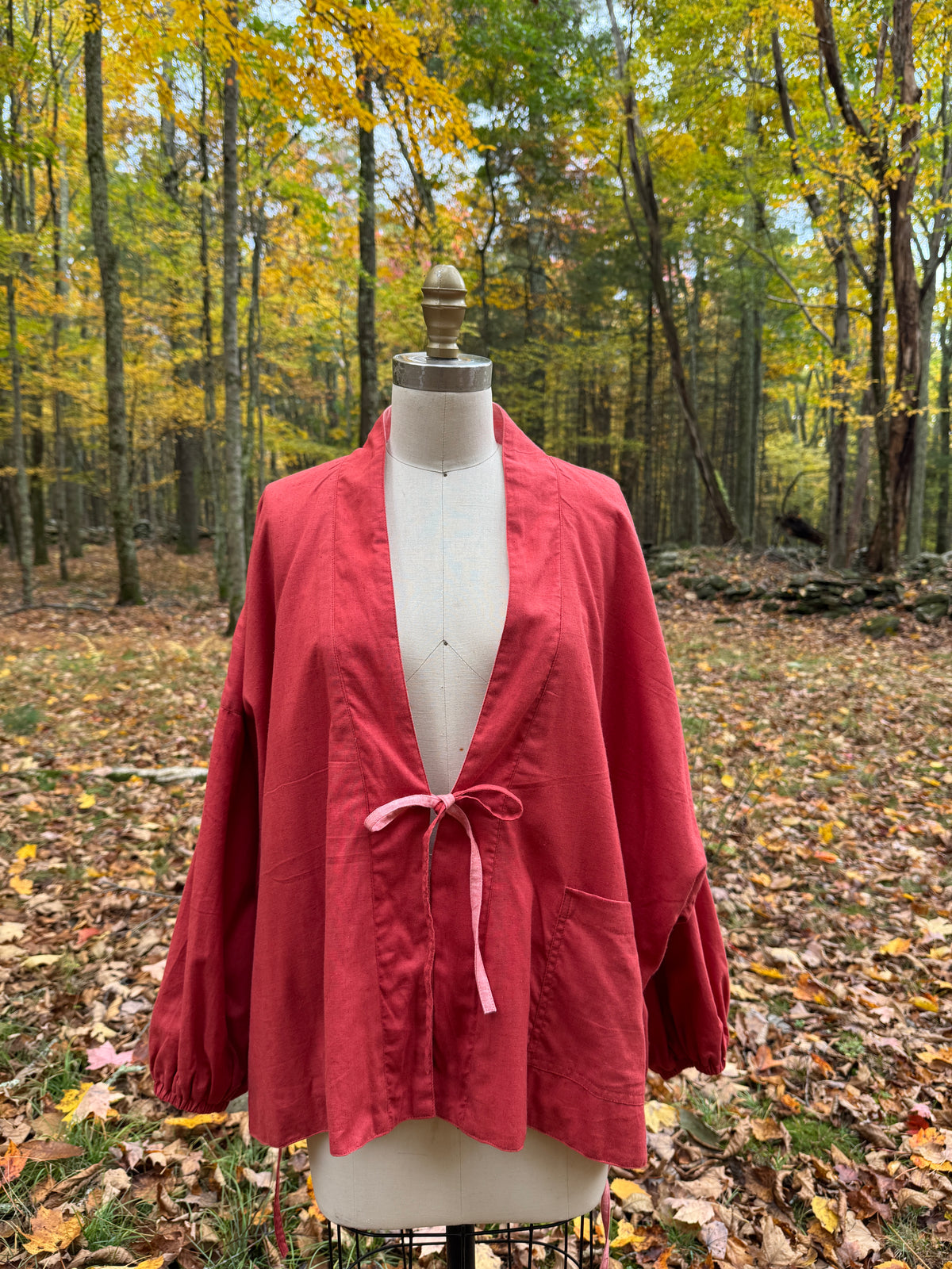 Red and pink reversible wrap jacket in organic cotton and hemp, red side out, tied at the center with a pink tie
