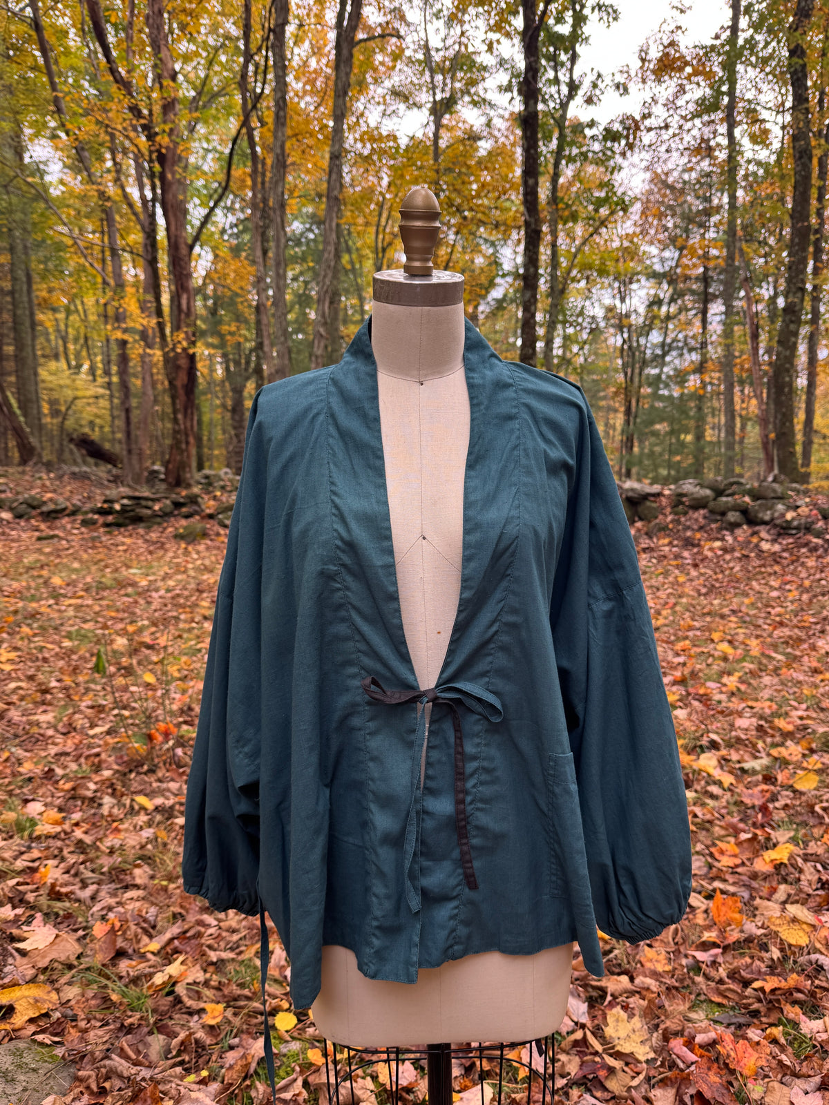 Teal and black reversible wrap jacket in organic cotton and hemp, teal side out, tied at the center